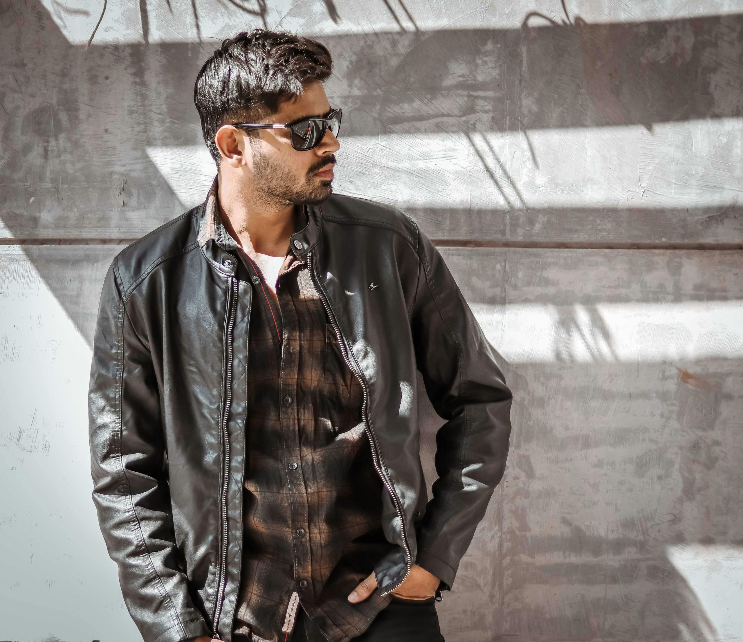 Fashionable man in leather jacket and sunglasses posing outdoors in Springfield, IL.